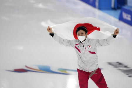 Miho Takagi of Japan carries her country's flag after setting an Olympic record and winning the gold medal in the women's speedskating 1,000-meter finals at the 2022 Winter Olympics, Thursday, Feb. 17, 2022, in Beijing. (AP)