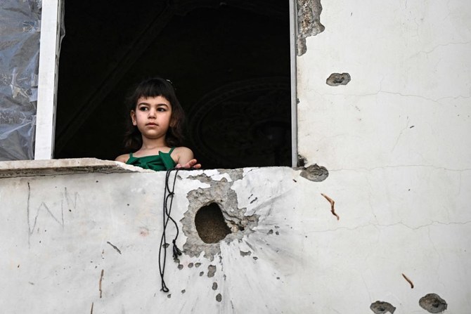2024年5月23日、占領下のヨルダン川西岸地区ジェニンで、イスラエル軍による空襲の後、破片が散乱した建物の窓から外を眺めるパレスチナ人の少女。(AFP＝時事）